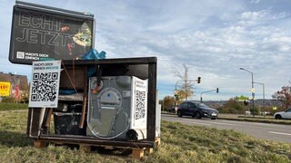Eine Installation aus illegal entsorgtem Müll mit Altreifen und Waschmaschine soll die Menschen aufrütteln.