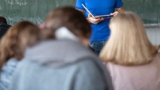 Ein Lehrer unterrichtet in einem Klassenzimmer. In Baden-Württemberg sind vor dem Schulstart noch 426 Lehrerstellen unbesetzt.