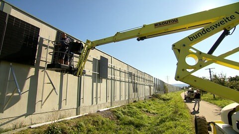 Stück für Stück werden die Module an der Lärmschutzwand angebracht.
