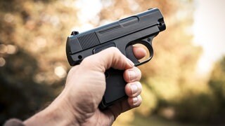 Eine männliche Hand hält eine Schusswaffe: Vor dem Mainzer Landgericht muss sich ein Mann wegen mehrerer Raubüberfälle vernatworten. Er soll sie auf einem Motorroller mit einer Schuswaffe in der Hand begangen haben. (Symbol)
