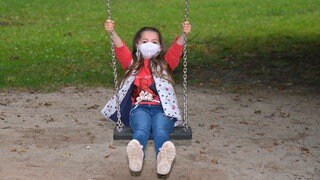 Ein Mädchen mit Gesichtsmaske schaukelt: Gibt es eine "Generation Corona"?