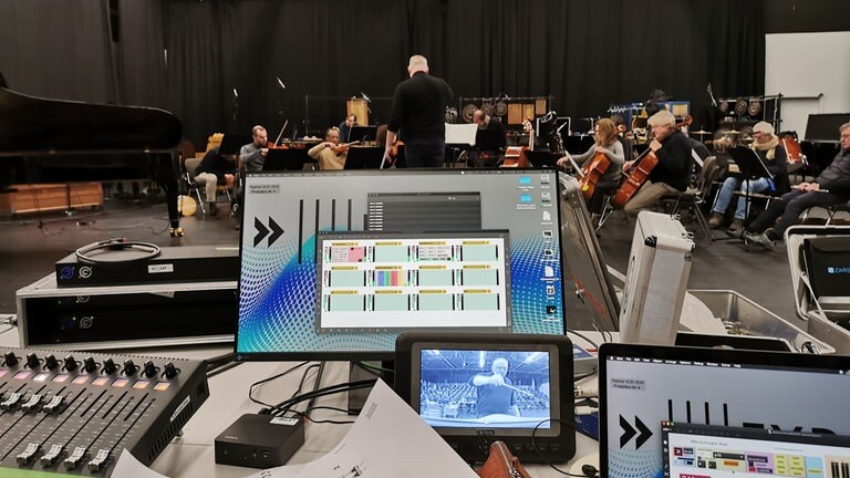 Mann probt ein Ensemble ein Stück mit Computern