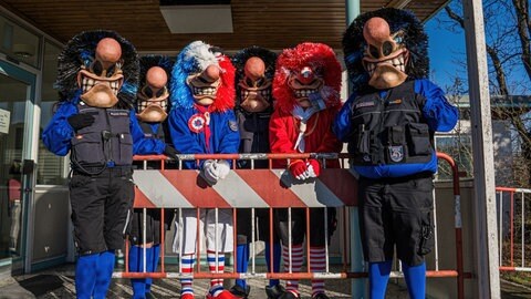Narren der "Grenz-Waggis" verkleidet als Zollbeamte und Grenzgänger aus dem Dreiländereck zwischen Deutschland, Frankreich und der Schweiz, bei der Fasnet 2026. Hier vor einer rot-weißen Grenzabsperrung.
