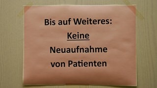Zettel mit dem Hinweis Bis auf Weiteres: Keine Neuaufnahme von Patienten an der Tür einer Hausarztpraxis