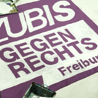 Auf einem lila Banner steht mit weißer Farbe geschrieben: Azubis gegen Rechts.