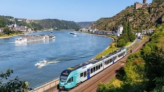 Eine Regionalbahn fährt am Rheinufer bei Sankt Goarshausen. Viele Ausflugsziele in Rheinland-Pfalz sind gut mit dem Zug erreichbar