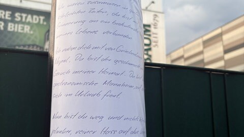 Ein handgeschriebener Brief klebt an einer Säule vor dem Eichbaum-Gebäude.