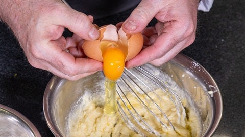 Dem Teig für die Cookies werden frische Eier hinzugefügt. Sie geben den Teig der Zitronenkekse Bindung.