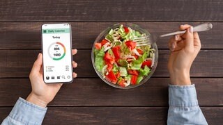 Schüssel mit Salt, daneben ein Handy mit dem Kalorien gezählt werden