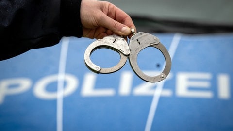 Ein Polizist hält während einer Kontrolle ein Paar Handschellen. Symbolbild. In Ludwigshafen hatte die Kriminalpolizei einen mutmaßlichen Drogenhandel beobachtet. Es gab zwei Festnahmen. Die Beamten fanden Kokain und viel Bargeld.