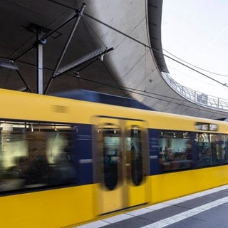 Eine gelbe Stadtbahn kommt aus einem Tunnel.