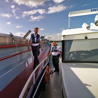 Zwei Wasserschutzpolizisten beim Übersteigen auf ein Güterschiff