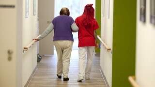 Eine Pflegekraft begleitet in einem Pflegezentrum eine Seniorin durch den Flur. Pflegekräfte in Baden-Württemberg bekommen nun einen mehr Gehalt.