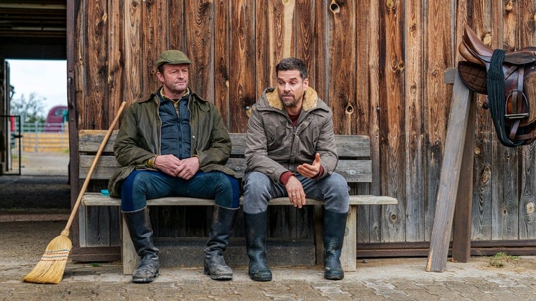 Bernd (Martin Wangler) und Andreas (Ralph Gassmann) sitzen auf einer Bank auf Bernds Gestüt