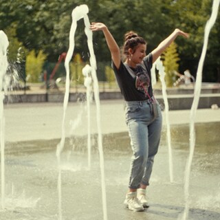 Zwei Teenagerinnen laufen durch einen Springbrunnen
