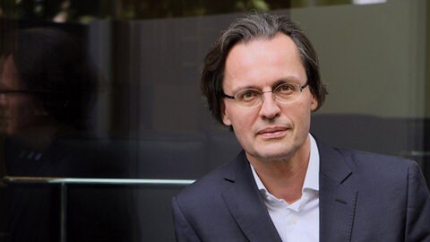 Prof. Bernhard Pörksen blickt in die Kamera. Warum können die Menschen heute offenbar nicht mehr empatisch miteinander reden, sich zuhören und gegenseitig verstehen? Das erforscht der Tübinger Medienwissenschaftler Prof. Bernhard Pörksen.  In SWR1 Leute sprechen wir mit ihm über sein Buch "Zuhören: Die Kunst sich der Welt zu öffnen".