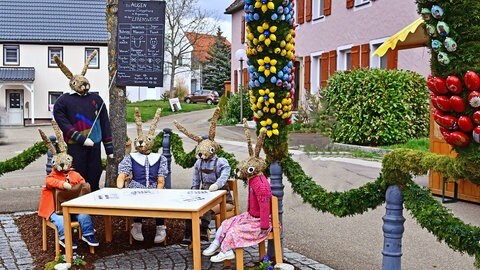 Beim Osterbrunnen in Schechingen sind mehrere Hasenfiguren aufgestellt, die eine Schulzszene darstellen. Der Lehrer bringt den Hasenkindern etwas über Tieraugen bei. 