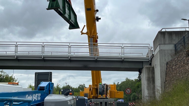 Eine riesige Traverse wird unter der Brücke montiert.