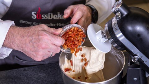 Zubereitung des Tomatenbrots: Getrocknete Tomaten werden zum Teig hinzugefügt.
