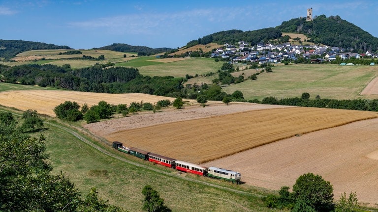 Auf der Brohltalbahn ist Diesellok D5 mit dem Vulkan-Express an der Burgruine Ohlbrück unterwegs.