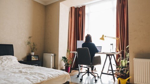 Frau sitzt im Schlafzimmer an einem Schreibtisch