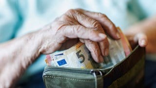 Eine 95-jährige Frau nimmt am 13.08.2025 Geldscheine aus ihrem Portemonnaie.