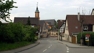 Hauptstraße von Merdingen. Im Hintergrund ist der rot-gelbe Kirchturm zu sehen.