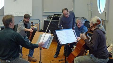 Männer von Streichquartett proben mit Komponisten