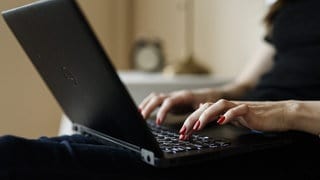 Frauenhand tippt am Laptop im Homeoffice