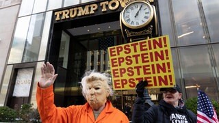 Ein Mann trägt eine Trumpmaske und einen orangen Gefängnisanzug bei einer Anti-Trump-Demonstration