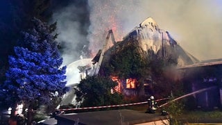 Einsatzkräfte der Feuerwehr löschen ein Feuer an einem Stall.