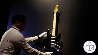 Eine Person mit weißen Handschuhen greift eine E-Gitarre. Die E-Gitarre ist teuerste E-Gitarre aller Zeiten. Rechts das SWR Logo für Leichte Sprache.
