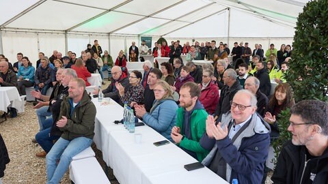 Menschen klatschen und lachen in einem Festzelt bei der Eröffnung des Windparks Münsingen-Magolsheim (Kreis Reutlingen).