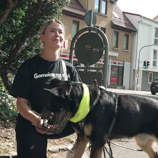 Michelle Langfeld kniet auf dem Boden. Vor ihr schnüffelt ihre Tierheimhündin an ihrer Hand.