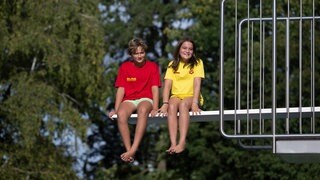 Die Schüler Leo und Marlene sitzen auf einem Sprungbrett im Freibad Nordheim.