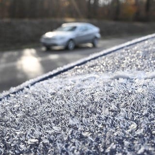 Auf einem Autodach eines Fahrzeugs, das am Rande einer befahrenen Straße steht, haben sich am Morgen bei winterlichen Temperaturen Eiskristalle gebildet. Es besteht die Gefahr von Glätte.