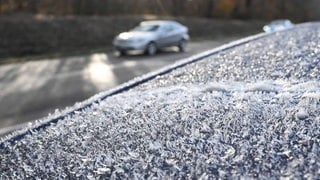 Auf einem Autodach eines Fahrzeugs, das am Rande einer befahrenen Straße steht, haben sich am Morgen bei winterlichen Temperaturen Eiskristalle gebildet. Es besteht die Gefahr von Glätte.