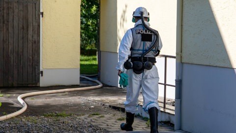 Ein Polizist der Brandermittlung geht in ein Haus (Symbolbild).