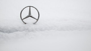 Ein Mercedes-Stern auf der schneebedeckten Motorhaube eines Autos