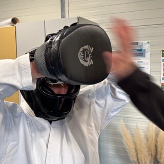 Beim Karatekurs schlägt eine Hand in einen Hand-Schoner
