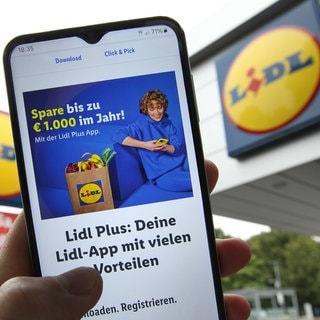 in Mann hält vor einer Filiale vom Discounter LIDL sein Smartphone in der Hand. Darauf sind Informationen über die APP Lidl Plus zu sehen. Das Stuttgarter Oberlandesgericht hat eine Klage gegen die LidlPlus-App abgewiesen. Der Verbraucherzentrale Bundesverband hatte von dem Discounter eine bessere Information der App-Kunden über die Nutzung und Weitergabe der Daten gefordert. 