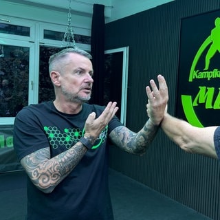 Trainer Thomas Mertz zeigt seinem Schüler die richtige Armhaltung. Damit soll der Angegriffene lernen, wie er durch seinen Kampfsport der Gewalt von Straftätern entgehen kann.