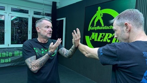 Trainer Thomas Mertz zeigt seinem Schüler die richtige Armhaltung. Damit soll der Angegriffene lernen, wie er durch seinen Kampfsport der Gewalt von Straftätern entgehen kann.