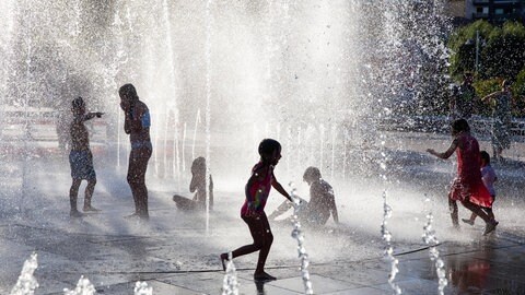 Kinder spielen am Brunnen