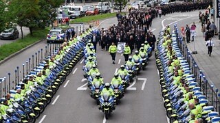 Polizeibeamte tragen bei einem Trauermarsch in Stuttgart für einen im Dienst verunglückten Polizisten ein Porträt des Kollegen.