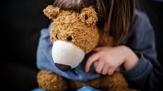 Ein Kind mit einem Teddybär in der Hand (Symbolbild).