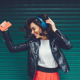 Junge Frau hört Musik und tanzt