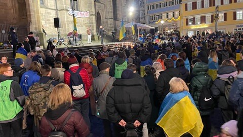 Ukraine-Fahnen, rund 250 Menschen vor der Tübinger Stiftskirche, auf deren Treppen singt ein Mann anlässlich des dritten Jahrestags des russischen Angriffs auf die Ukraine