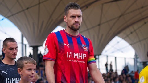 Kapitän Patrick Mainka vom 1. FC Heidenheim läuft mit einem Jungen neben ihm zum DFP-Pokalspiel gegen den SSV Jeddeloh ins Stadion.