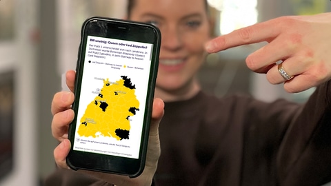 Cora Klausnitzer zeigt mit dem Finger auf die Statistik der SWR1 BW Hitparade 2025 auf ihrem Smartphone